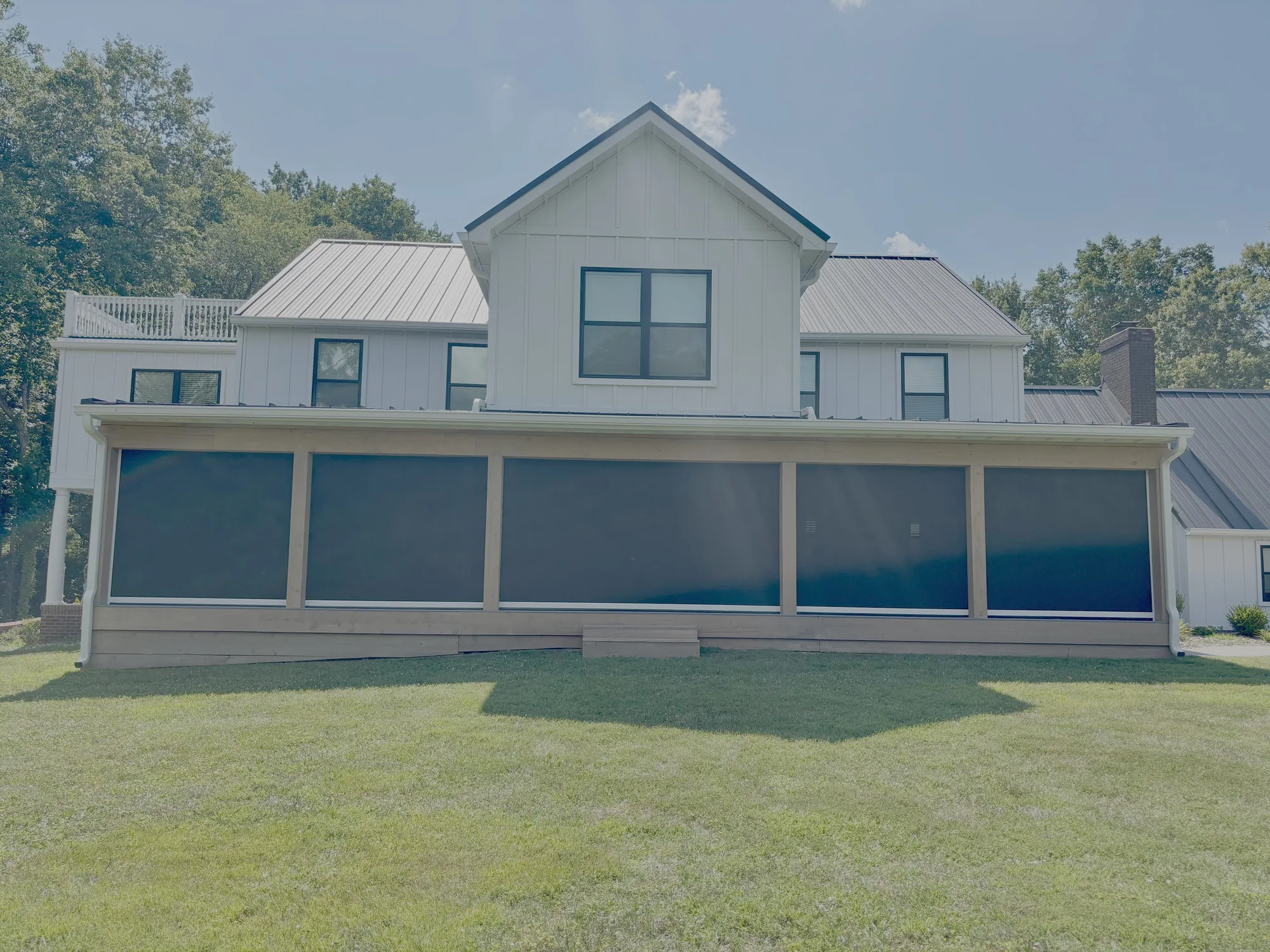 Exterior shades across the wrap porch of a white Texas farmhouse